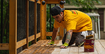 Painter applying fresh exterior stain to home siding